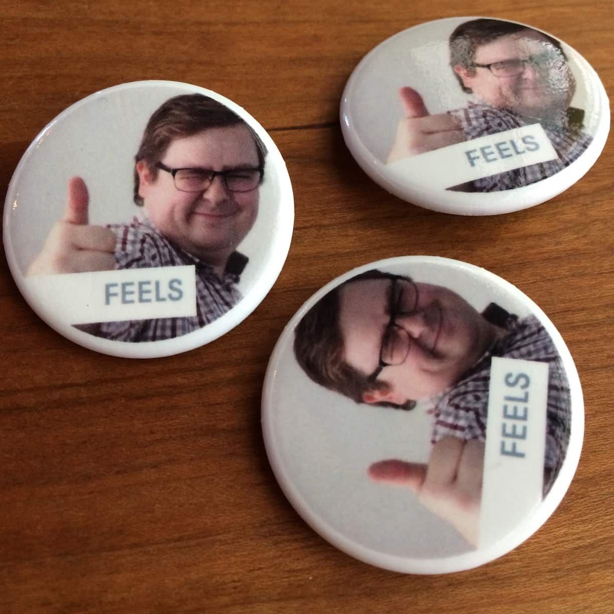 Photo of several buttons with my face on them, with the word FEELS