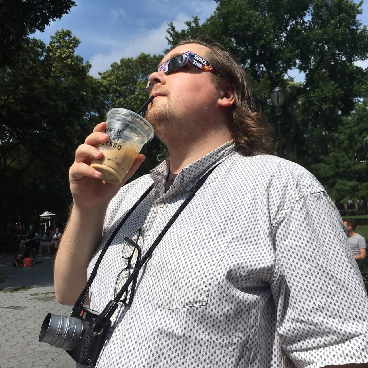 Photo of me, sipping coffee, while looking up directly at the sun, and I'm wearing eclipse-watching glasses