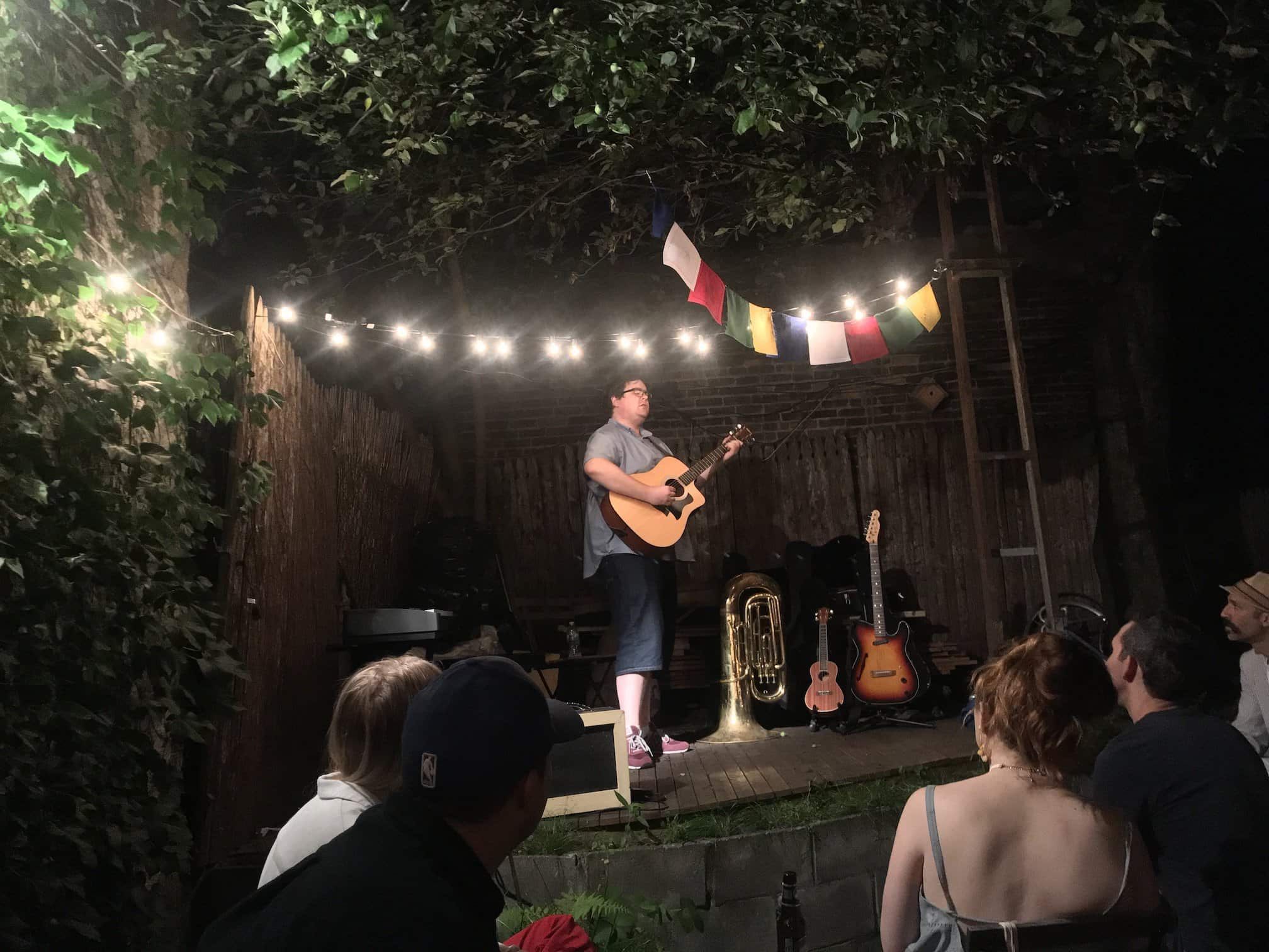 Photo of me in a backyard playing guitar in front of people