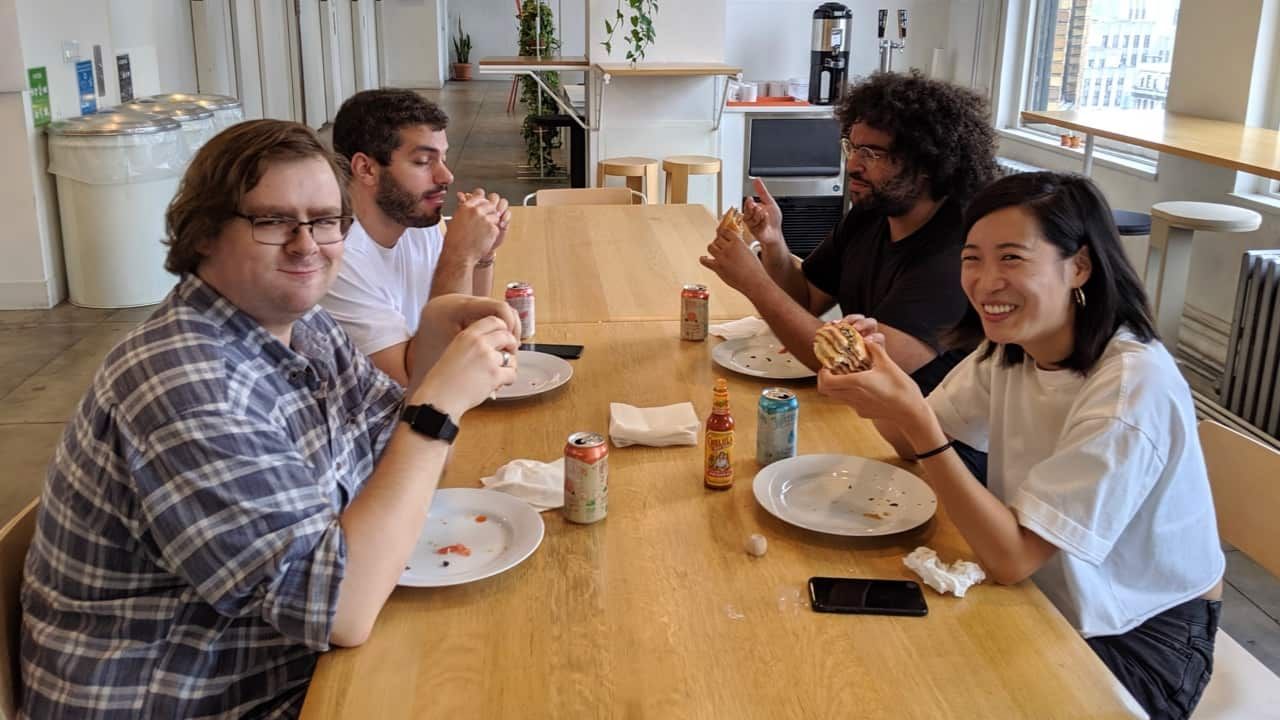 Photo of several of the Purchase team members apparently laughing at their sandwiches