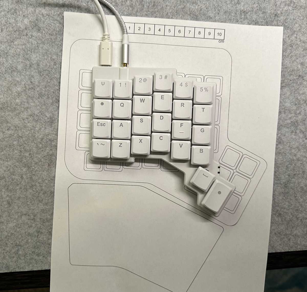 Photo of one half of the Voyager on a to-scale print-out of the ErgoDox EZ